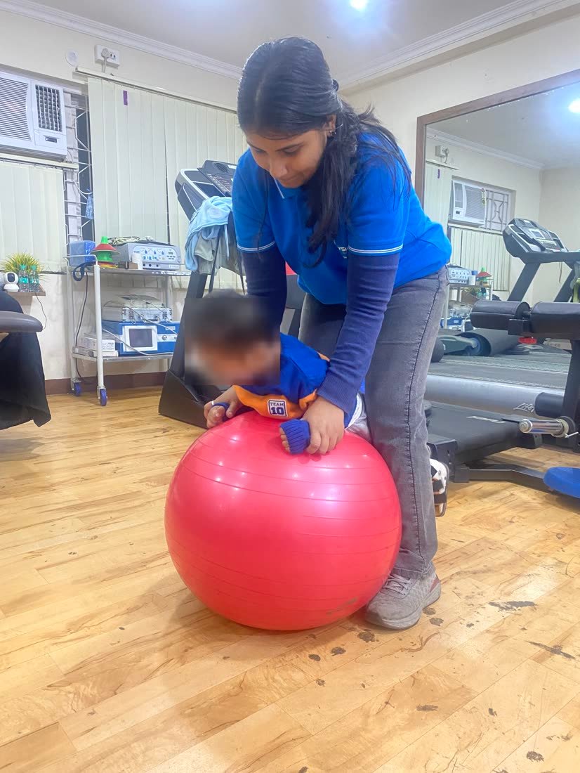 Female physiotherapist supporting an infant in balance work at Physiotrix Ballygunge